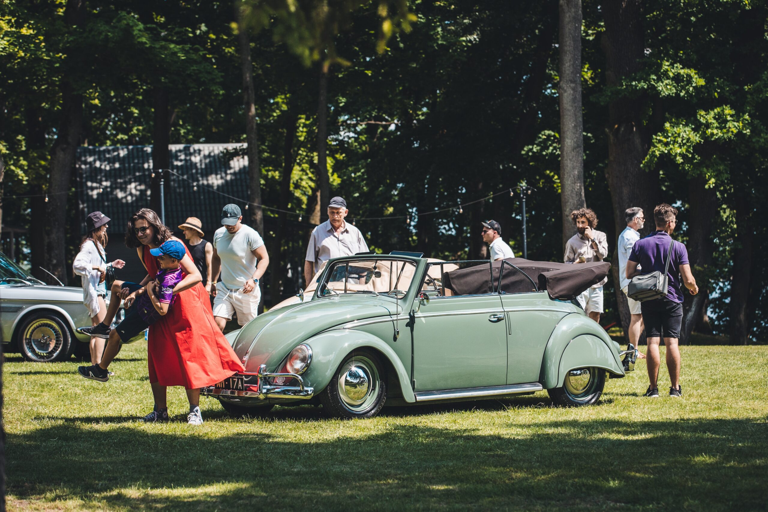 a group of people standing around a green car