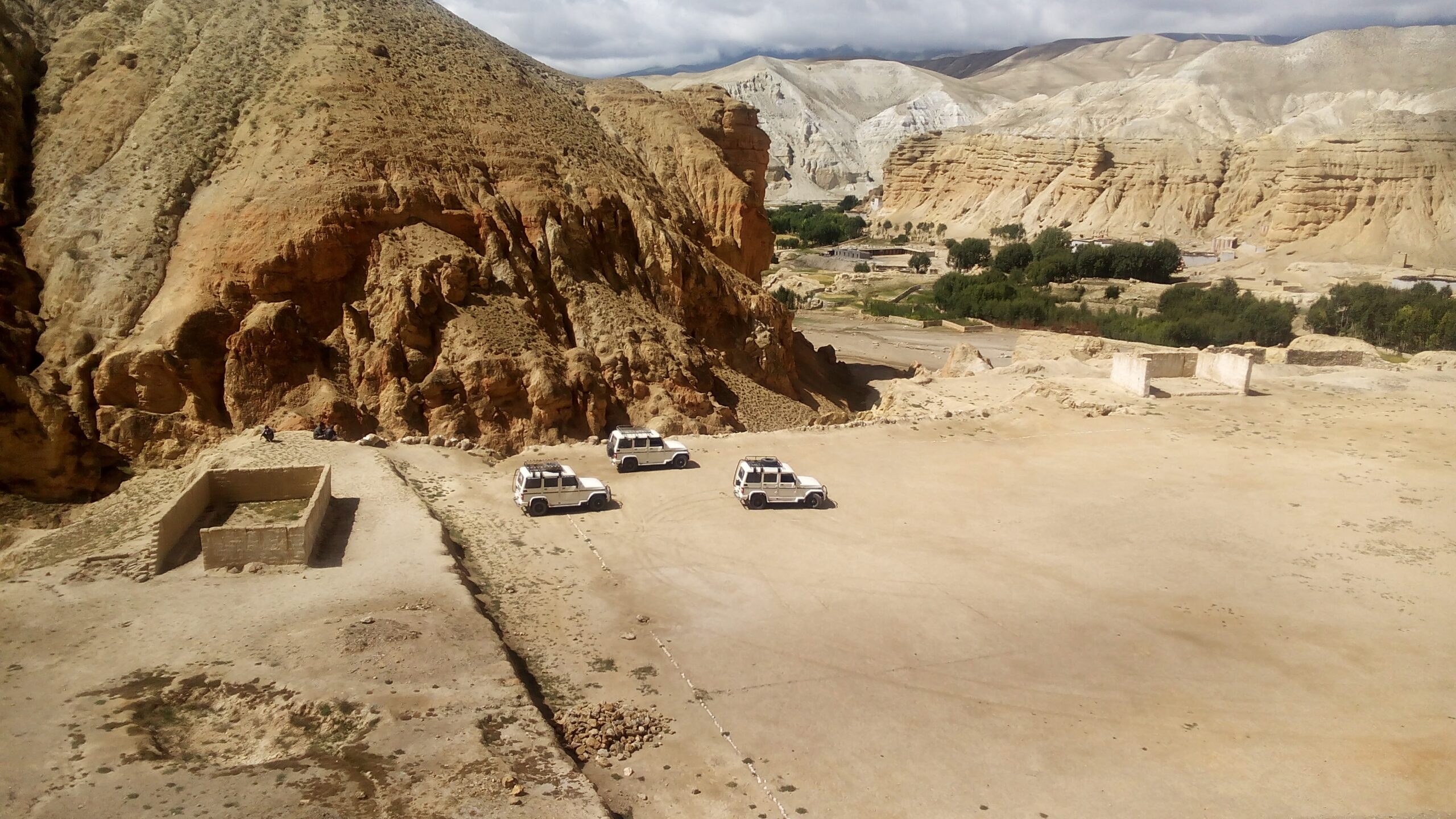 aerial photography of three white vehicles beside brown mountain during daytime