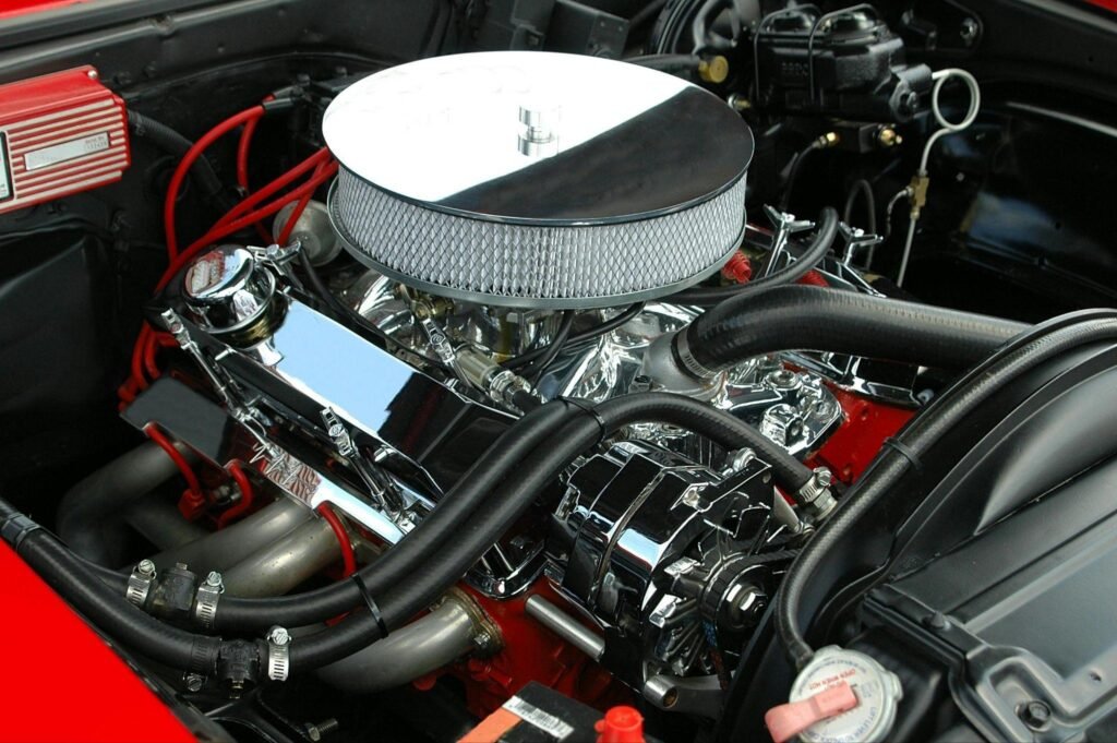 Well maintained classic car engine with lots of chrome, in a bright red car.