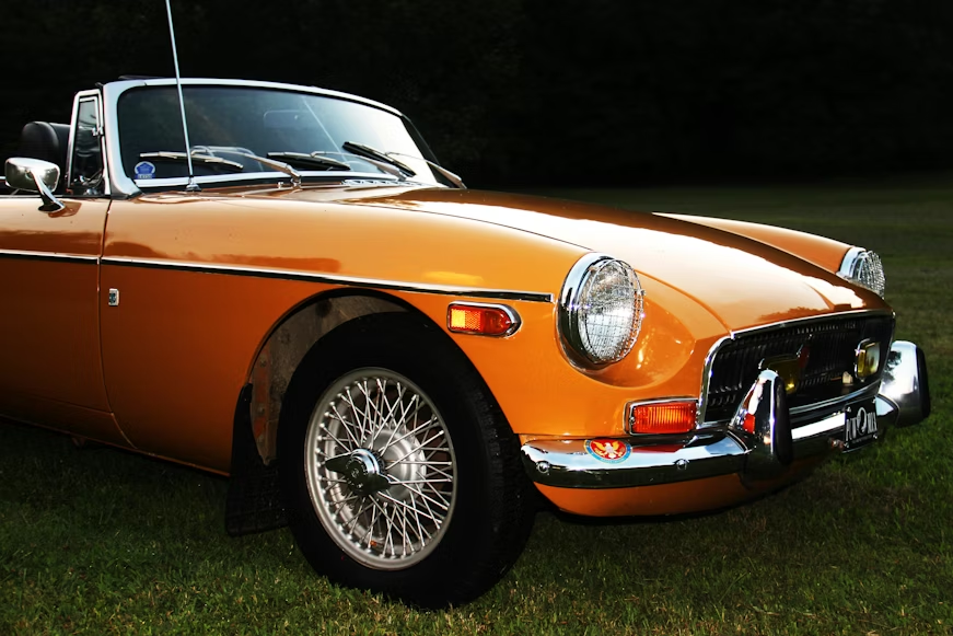 Classic MG MGB roadster in orange with chrome wire spoke wheels, vintage British sports car
