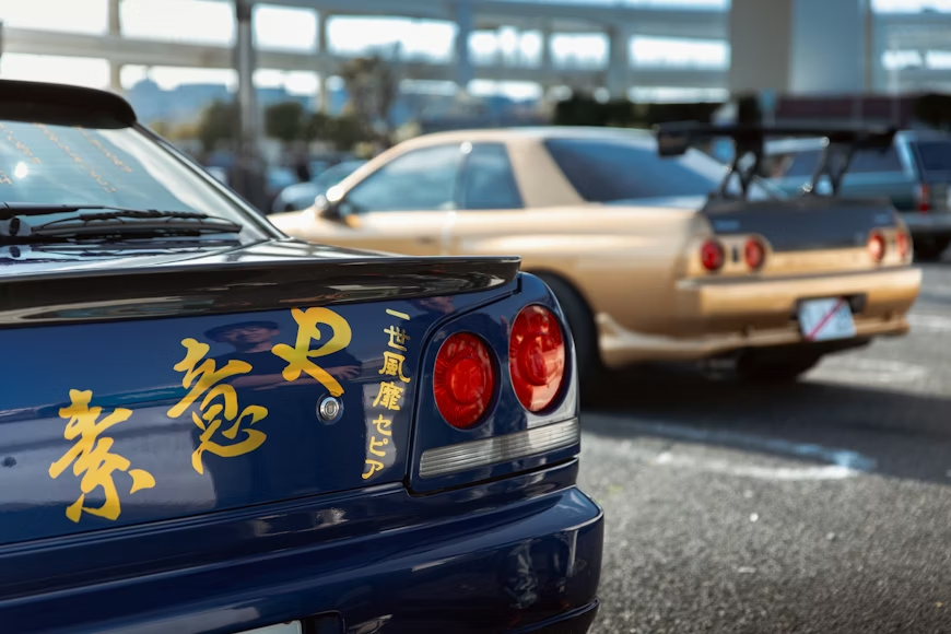 Modified Nissan Skyline GT-R with Japanese kanji decals at a JDM car meet, representing Japanese import tuner culture